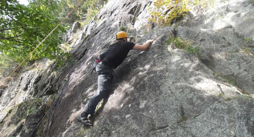 A person wearing a helmet is attached to ropes as they climb a rock face. 